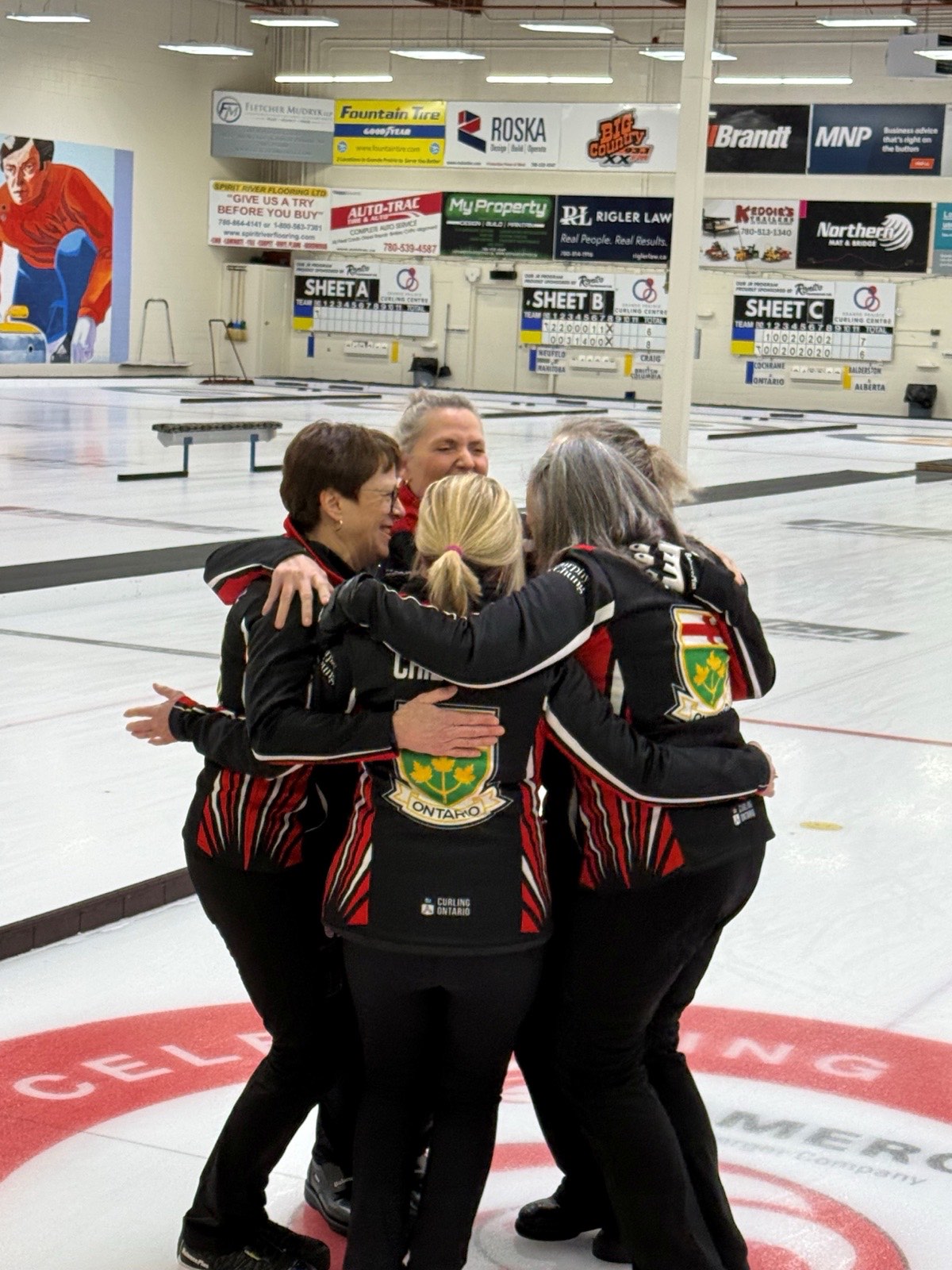 Team Ontario's women's rink celebrating in a group hug on the ice